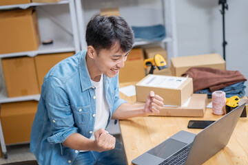 Young Asian man, distributor, online shop owner, small business owner, standing in warehouse, showing happy gesture of receiving product order.