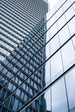 A towering modern skyscraper featuring reflective glass windows, captured from a low-angle view, highlighting the contemporary architecture and urban atmosphere.