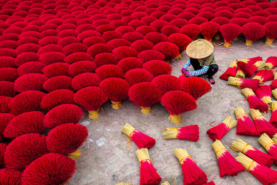 View of colourful incense drying in the sun with workers in conical hats, Quang Phu Cau village, Vietnam.