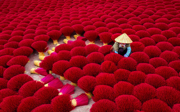 View of colourful joss sticks drying in the sun with workers in traditional attire, Quang Phu Cau village, Hanoi, Vietnam.