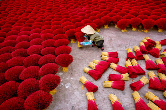 View of colourful joss sticks drying under the sun with workers in Quang Phu Cau village, Vietnam.