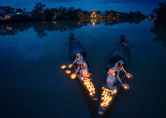 View of graceful vietnamese ladies in ao dai with glowing lanterns on a tranquil river at dusk, Hue, Vietnam.