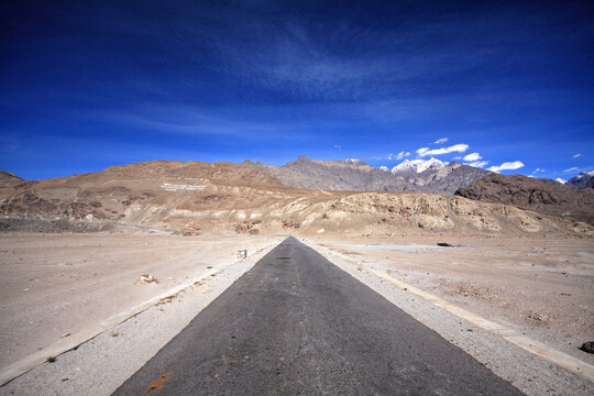 View of the winding road through majestic mountains and arid desert under a vast sky, Skardu, Pakistan.