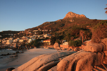 View of beautiful Camps Bay beach with tranquil ocean and scenic Lions Head mountain at sunset, Cape Town, South Africa.