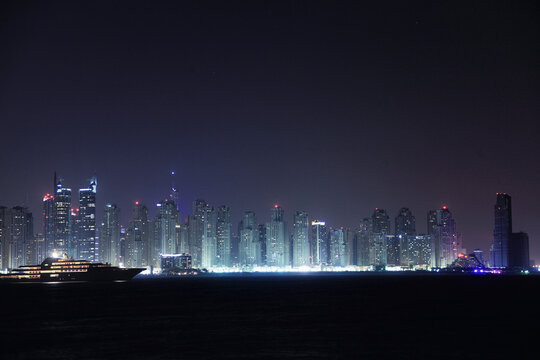 View of illuminated skyline with modern skyscrapers in a colorful desert city, Dubai, United Arab Emirates.