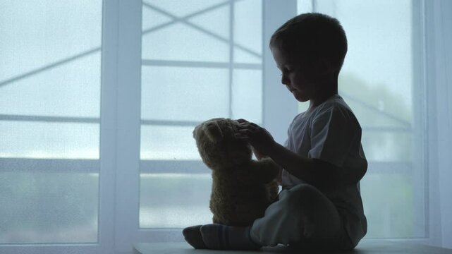Kid hugging teddy bear room facing stress violence. Violence leaves child stress fear. Kid seeks solace teddy bear stressful room. Stress and violence. bear provides comfort to child facing violence
