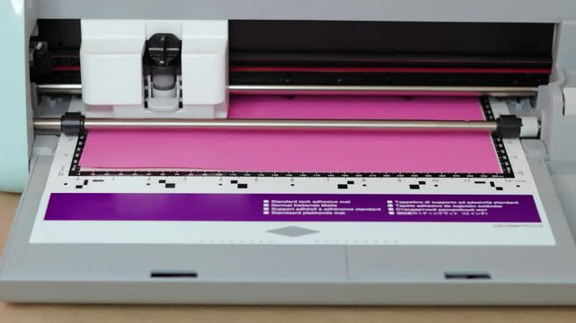 Cutting plotter processing vibrant pink cardboard with precision