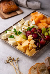 Cheese plate with different cheese, grapes and melon.