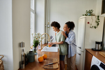 A loving couple shares a tender moment while washing dishes together.