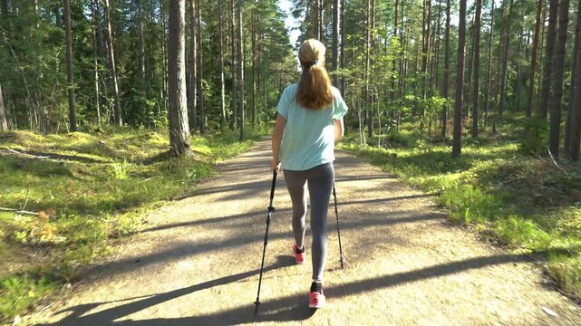 Active woman doing Nordic walking in a national park in Finland, doing sports in the park, staying fit by exercising