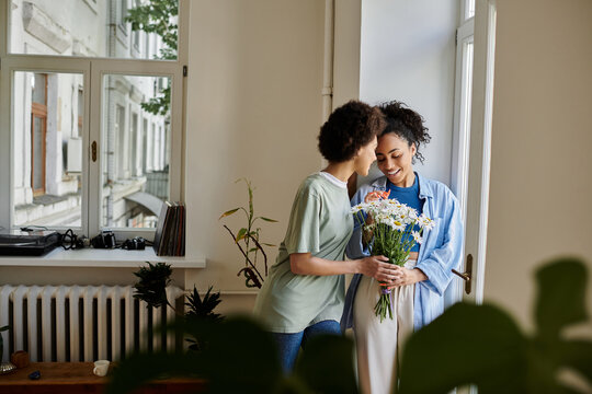 A loving couple shares a tender moment while enjoying flowers indoors.