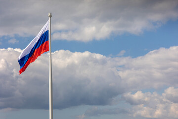 Flag of Russian Federation is flying in air on blue sky and white cumulus clouds. National flag of...