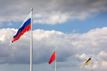 Historical flags of Russian Empire, USSR and State Flag of Russian Federation is flying in air on blue sky and white cumulus clouds. National flags of Russian. National flag of Russian