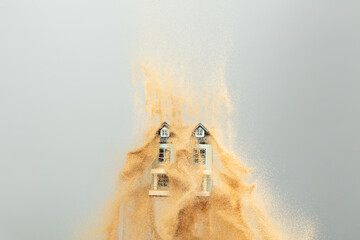 Strong wind of sand attack house with insurance create loss damage environment. Sand storm hit House as natural disaster from climate change global warming. Gray background isolated © Jade