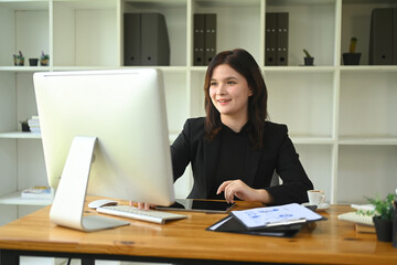 Confident young businesswoman review financial data on computer monitor