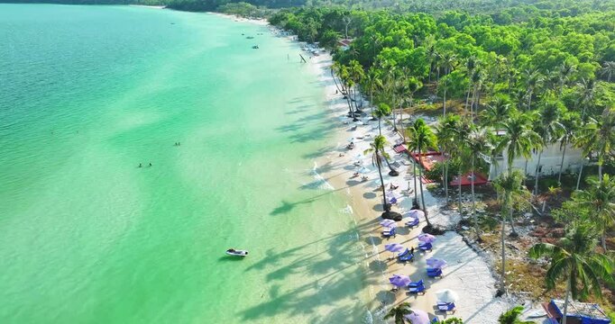 Drone aerial view in Vietnam flying over Phu Quoc island Sao beach, white sand, crystal clear blue turquoise water, green palm trees and people walking on a sunny day