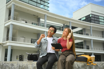 University student sitting on a ledge in front of building and talking to each other at break time