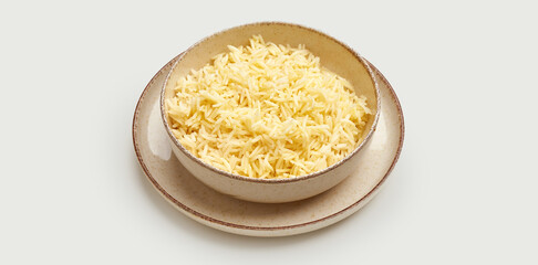 A bowl of fluffy, white basmati rice is presented on a beige plate against a clean white background.