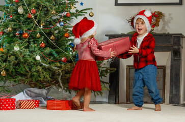 Children in Santa hat share holiday presents near decorated tree