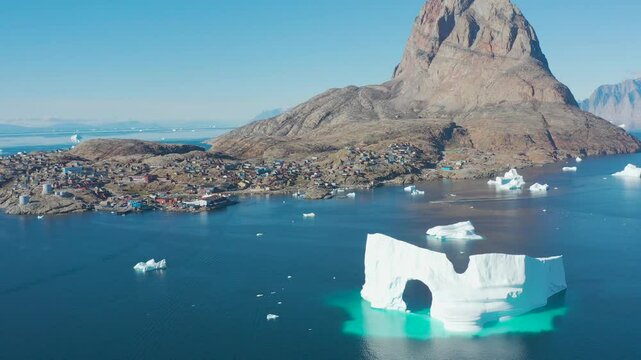 Uummannaq is the second largest city in Greenland. Huge cracked glacier with arch floating cold blue polar water. Natural beauty of towering glacier. Ecology, climate change global warming, close up