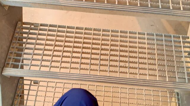 Metal Staircase with Grating Treads. A close-up view of a metal staircase with grating treads. The treads are made of a grid pattern, and the staircase is made of metal.