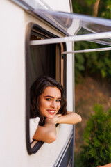 Young woman peeking out of camper window.