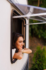 Young woman peeking out of camper window.