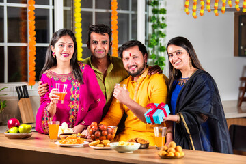 Happy Indian family and friends celebrating Diwali at home, sharing food and laughter