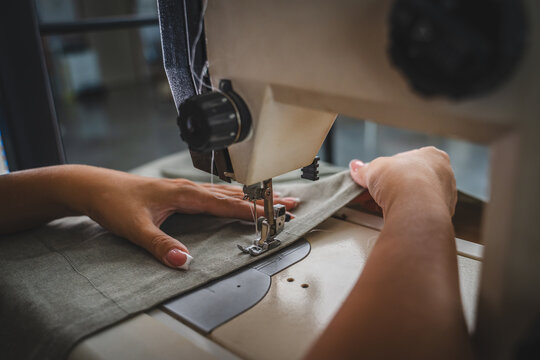 Close up on hands of unknown woman sewing on electric sewing machine