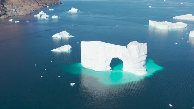 Uummannaq is the second largest city in Greenland. Huge cracked glacier with arch floating cold blue polar water. Natural beauty of towering glacier. Ecology, climate change global warming, close up