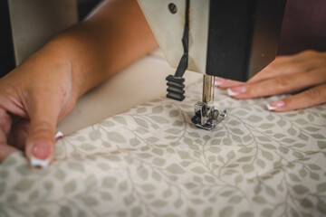 Close up on hands of unknown woman sewing on electric sewing machine