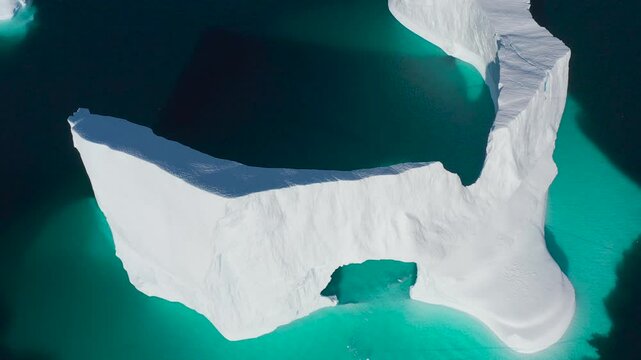 Blue arctic iceberg arch melting underwater. Huge cracked glacier floating cold blue polar water. Natural beauty of towering glacier. Glacier under blue sky. Ecology, climate change global warming