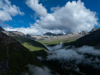 Aerial view of beautiful high altitude snow capped mountain waterfall and forest landscape