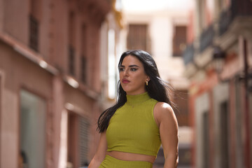 Fototapeta premium Portrait of a young, beautiful, brunette, Latina woman, wearing a green suit, with a distracted and lost look. Concept beauty, fashion, trend, city.