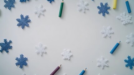 This flat lay features colored snowflakes surrounded by colored pencils on a white background, inviting children to engage in creative winter coloring activities