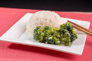 cooked Broccoli with white rice on a white plate on a black background.food concept.diet. food