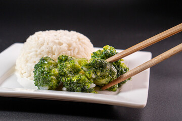 cooked Broccoli with white rice on a white plate on a black background.food concept.diet. food