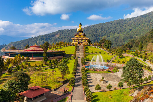 Ravangla Buddha Park, Sikkim, India, with a large golden Buddha statue, green hills, blue sky, and landscaped gardens. The park&rsquo;s serene environment and pathways make it a cultural landmark