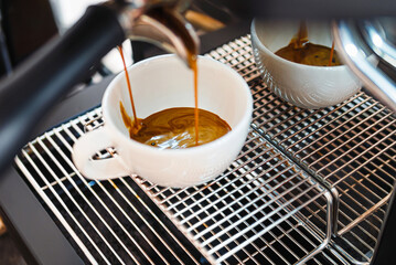 Close-up of espresso pouring from the coffee machine into a coffee cup. Professional coffee brewing
