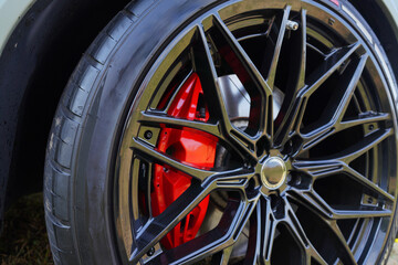 Fototapeta premium Alloy wheel with calipers and racing brakes of the sport car. Racing brake disc and low profile tyres. Race car test driving. Lower-profile tires of drag and drift cars. High-performance sports cars.