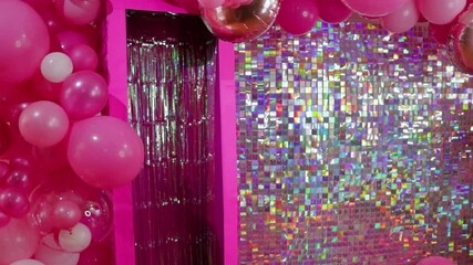 Bright pink and silver party decor with balloons and shimmering backdrop