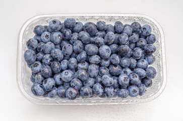Top view transparent box with fresh blueberries isolated on white. Antioxidants, vitamins, health.
