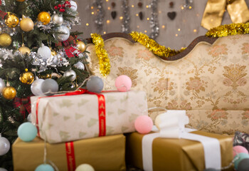 New Year Eve in room with a sofa and different gift boxes on it and big decorated Christmas tree next to it