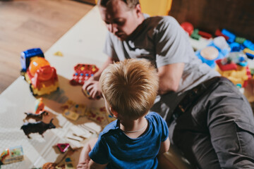 Little boy with his dad playing with toys at home. Happy father and son spending time together
