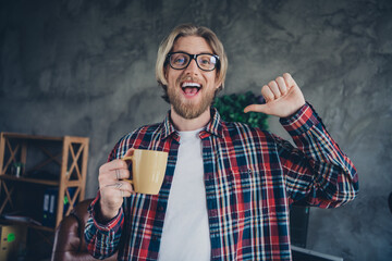 Portrait photo of young blond hair business man personal branding pointing finger himself holding cup tea indoors loft design modern office
