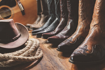 Cowboy hat and four pairs of cowboy boots, country music festival live concert concept with acoustic guitar