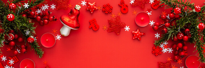 Red Christmas background with fir branches and red Christmas tree toys and balls and candles, banner