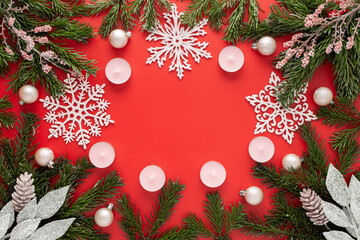 Red Christmas background with fir branches and pink Christmas tree toys and snowflakes and candles