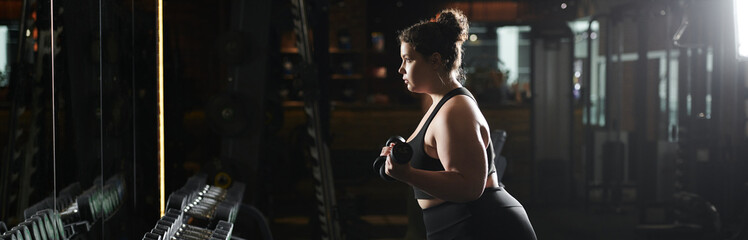 A young woman exercises in active wear, showcasing her strength and body positivity in the gym.
