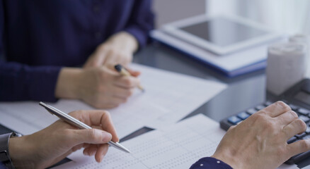 Female accountants or auditors reviewing financial data in office. Professionals analyzing paper reports and using calculator, close up view. Audit and taxes in business